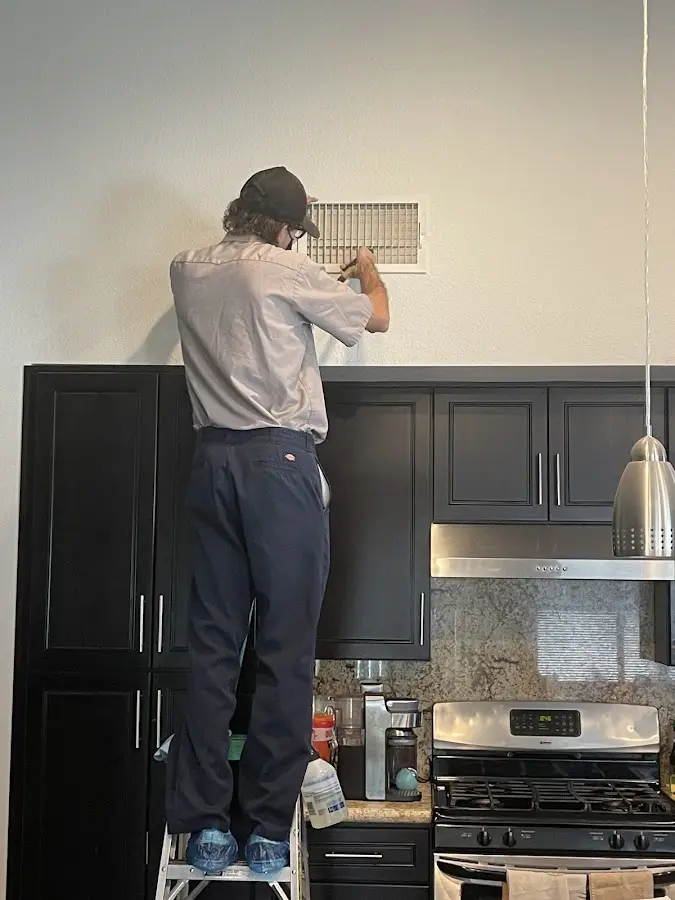 Technician inspecting an air vent during HVAC service in Elk Grove